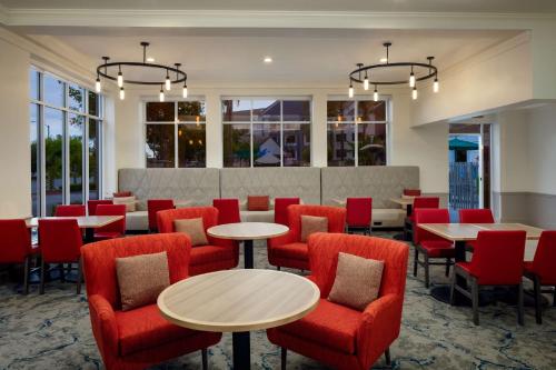 a restaurant with red chairs and tables and windows at Hilton Garden Inn Arcadia/Pasadena Area in Arcadia