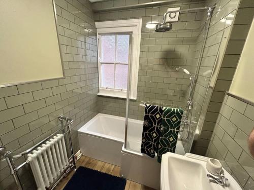 a bathroom with a shower and a tub and a sink at The Green House Hythe in Kent