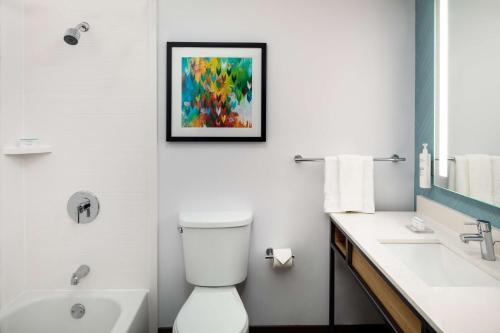a bathroom with a white toilet and a painting on the wall at Hilton Garden Inn Arcadia/Pasadena Area in Arcadia