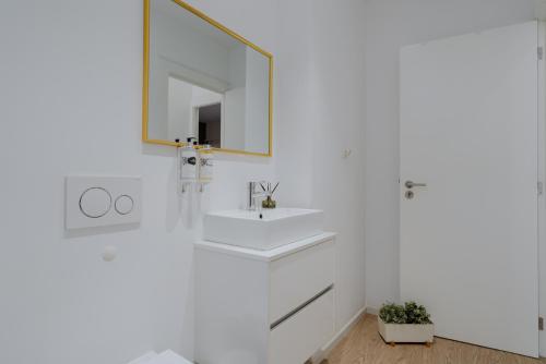 een witte badkamer met een wastafel en een spiegel bij Downtown Terrace Flat with AC and Patio - feel like a local in Porto