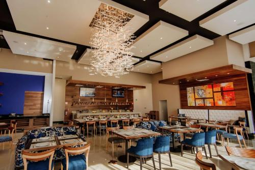 a restaurant with tables and chairs and a chandelier at Hilton Garden Inn Puebla Angelopolis in Puebla