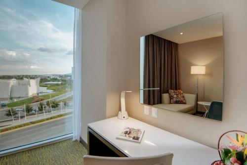 Habitación de hotel con escritorio y espejo grande. en Hilton Garden Inn Puebla Angelopolis, en Puebla