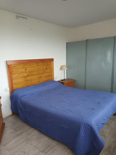 a bedroom with a blue bed and a wooden headboard at Playa Dorada, fte mar, gran 2 amb 4 pax, quincho parrilla in Santa Clara del Mar