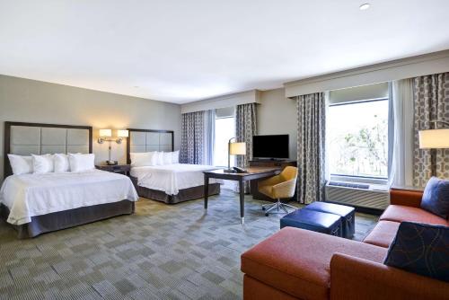 a hotel room with two beds and a living room at Hampton Inn & Suites Dallas/Plano-East in Plano