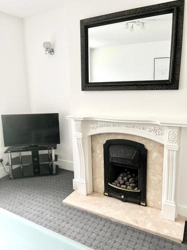 a fireplace with a mirror above it and a television at Convenient & Modern Private Bedroom Space near Barnsley Hospital in Barnsley