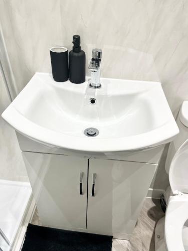 ein Badezimmer mit einem weißen Waschbecken und einem WC in der Unterkunft Convenient & Modern Private Bedroom Space near Barnsley Hospital in Barnsley