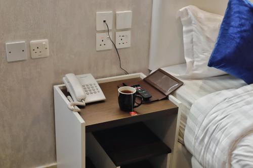 a bed room with a desk with a phone and a cup of coffee at شقق زوايا الماسية العوالي in Al Madinah