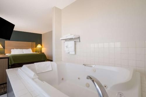 baño con bañera y cama en Quality Inn Denver Northeast Brighton, en Brighton