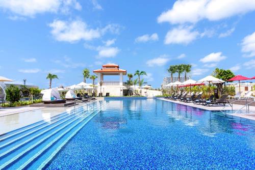 a pool at a resort with chairs and umbrellas at DoubleTree by Hilton Okinawa Chatan Resort in Chatan
