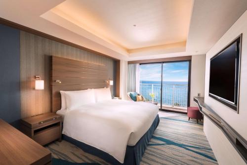 a hotel room with a large bed and a large window at DoubleTree by Hilton Okinawa Chatan Resort in Chatan