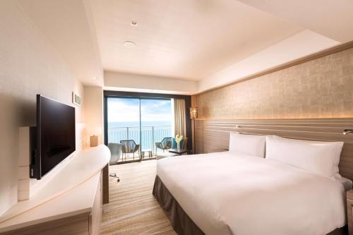 a hotel room with a bed and a television at DoubleTree by Hilton Okinawa Chatan Resort in Chatan