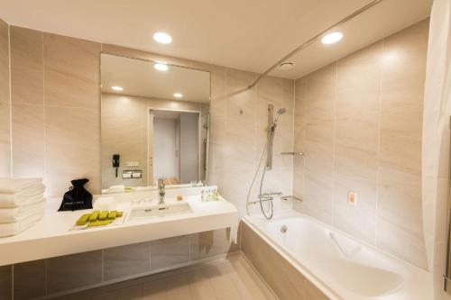 a bathroom with a sink and a tub and a mirror at DoubleTree by Hilton Okinawa Chatan Resort in Chatan