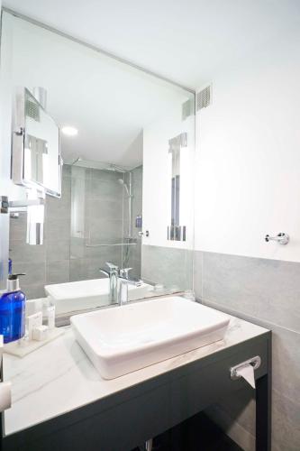 a white bathroom with a sink and a mirror at Radisson Blu Hotel Dortmund in Dortmund