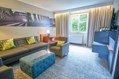 a living room with a couch and a chair at Radisson Blu Hotel Dortmund in Dortmund