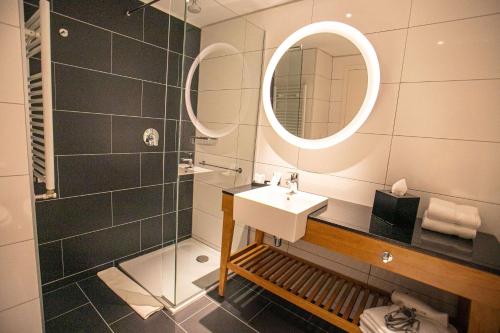 a bathroom with a sink and a mirror and a shower at Hampton By Hilton Bariloche in San Carlos de Bariloche