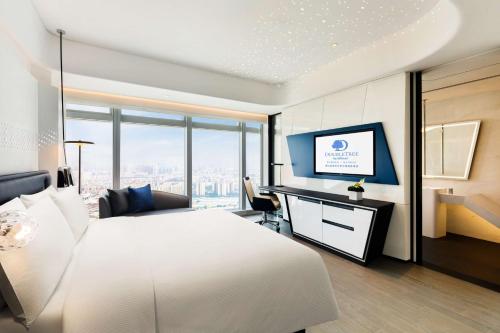 a bedroom with a white bed and a desk with a television at Doubletree by Hilton Foshan Nanhai-Free Canton Fair Shuttle Bus in Foshan