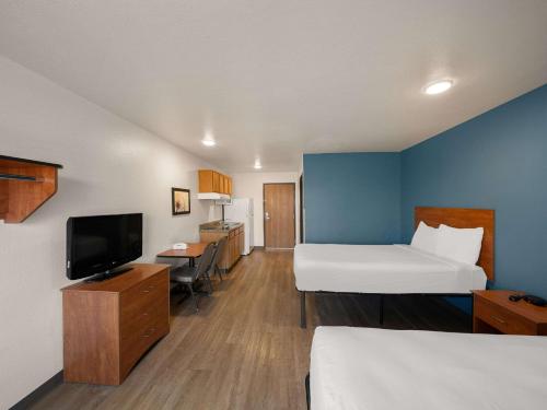 a hotel room with two beds and a flat screen tv at WoodSpring Suites Dallas Rockwall in Rockwall