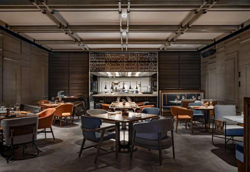 a restaurant with tables and chairs and a kitchen at Canopy by Hilton Hangzhou West Lake in Hangzhou