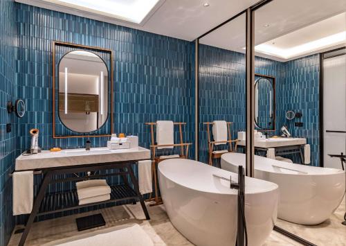 een badkamer met een bad, een wastafel en een spiegel bij Canopy by Hilton Hangzhou West Lake in Hangzhou