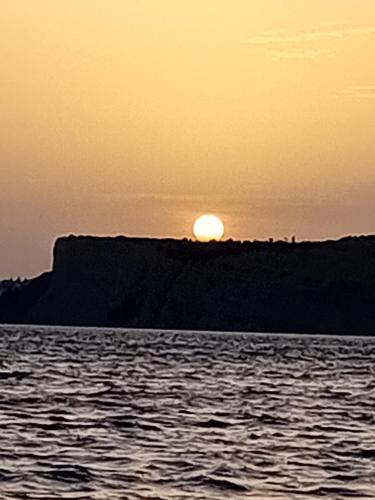 einen Sonnenuntergang über dem Meer mit der Sonne auf einer Klippe in der Unterkunft The Boat in Lagos