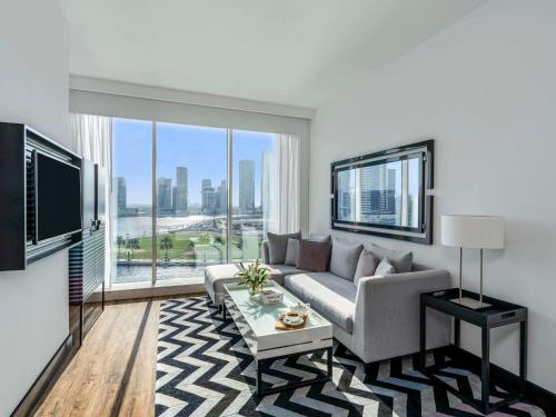 a living room with a couch and a large window at Pullman Dubai Downtown in Dubai