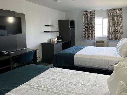 Habitación de hotel con 2 camas, escritorio y TV. en Studio 6 Suites Delano, CA, en Delano