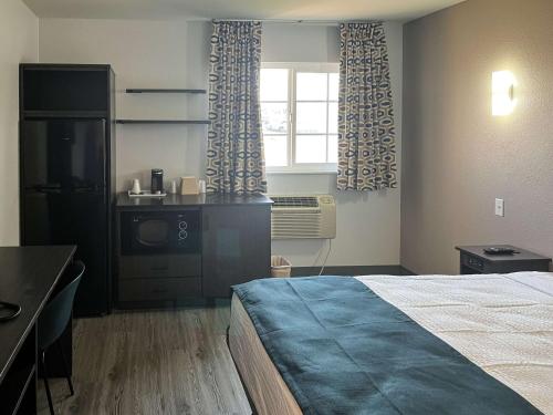 a bedroom with a bed and a television and a window at Studio 6 Suites Delano, CA in Delano