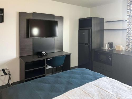 a bedroom with a bed and a desk with a television at Studio 6 Suites Delano, CA in Delano