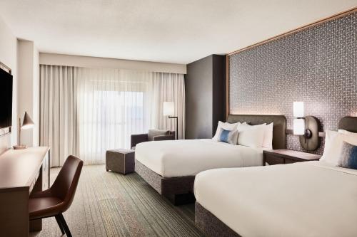 a hotel room with two beds and a desk at Renaissance Phoenix Glendale Hotel & Spa in Glendale