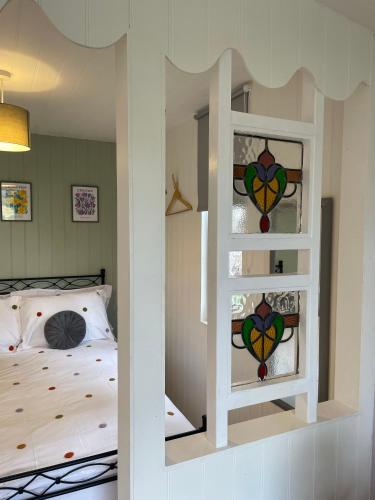 a bedroom with a bed with stained glass windows at Pwllglas Bach - Spacious Cabin in Machynlleth