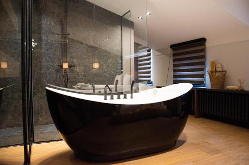 a bathroom with a black tub and a glass shower at Kristall Apartments Premium in Šabac