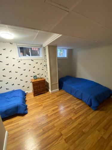 a bedroom with two blue beds and a wooden floor at Spacious Guest house -walkout Basement- 4 guests! -dedicated workspace-No Pet! No Cooking! No Smoking! No Party! in Ottawa