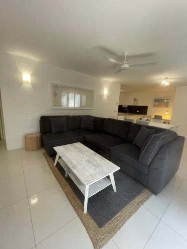 a living room with a black couch and a coffee table at Myuna Holiday Apartments in Noosa Heads