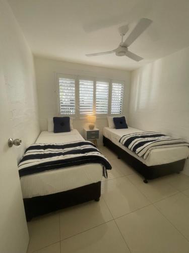 a bedroom with two beds and a ceiling fan at Myuna Holiday Apartments in Noosa Heads