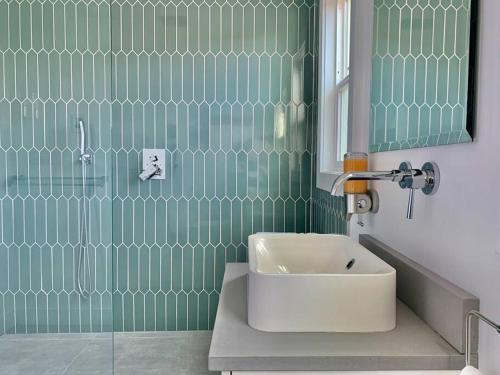シアトルにあるModern Amenities & Chic Design in Heart of Seattleの緑のタイル張りのバスルーム(シンク、シャワー付)