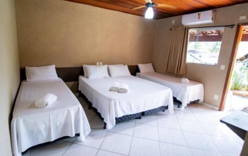 a room with two beds with white sheets at Pousada Divino Canto in Olímpia