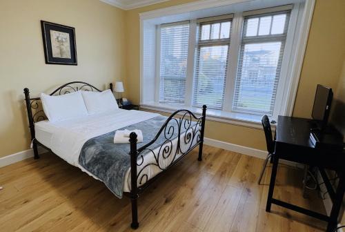 1 dormitorio con 1 cama, 2 ventanas y escritorio en Vancouver Metrotown Guest House 8 mins walk to Sky Train en Burnaby