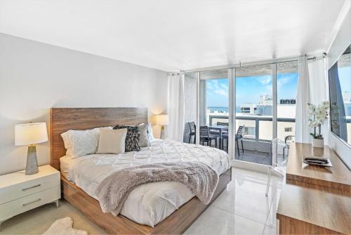 a white bedroom with a large bed and a balcony at Champagne & Ice! Water Views, 2 Private Balconies! in Miami
