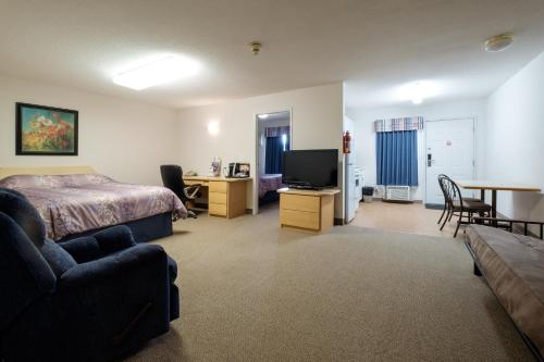 Schlafzimmer mit einem Bett, einem Schreibtisch und einem TV in der Unterkunft Perfect Inns & Suites in Weyburn