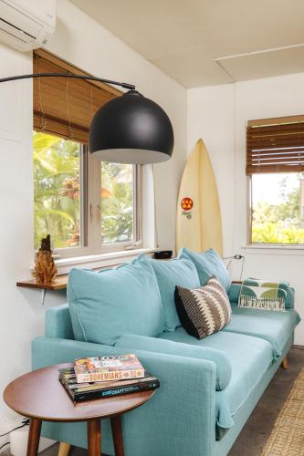 a blue couch in a living room with a surfboard at Earthy Beach House in Kailua-Kona