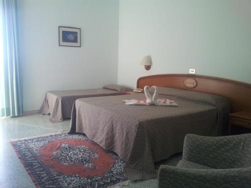 a hotel room with two beds and a chair at Hotel Eden in San Domino