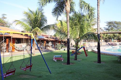 a playground with swings and palm trees next to a pool at Pousada Divino Canto in Olímpia