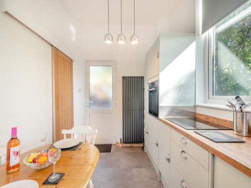 a kitchen with white cabinets and a wooden table at Lincumtoy in Ballantrae