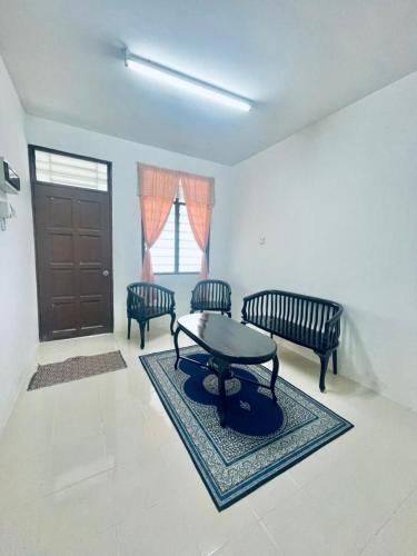 uma sala de estar com uma mesa e duas cadeiras em Ast kok Lanas homestay em Ketereh