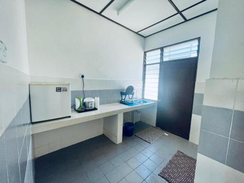 a kitchen with a counter with a refrigerator and a window at Ast kok Lanas homestay in Ketereh