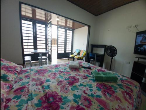 a bedroom with a bed with a flowered blanket on it at Apto Hospedaje Llanero in Acacías