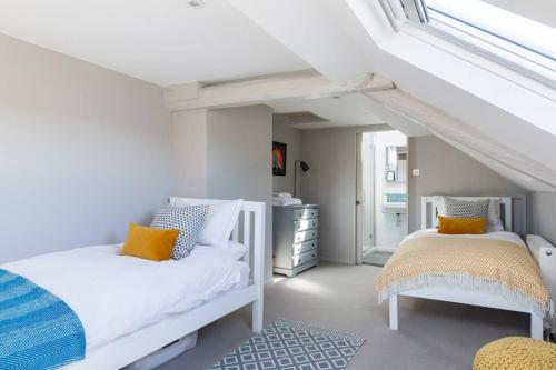 a white bedroom with two beds and a window at Anchor Weighbridge House, Winchcombe - 4 bed, 4 bath in Winchcombe
