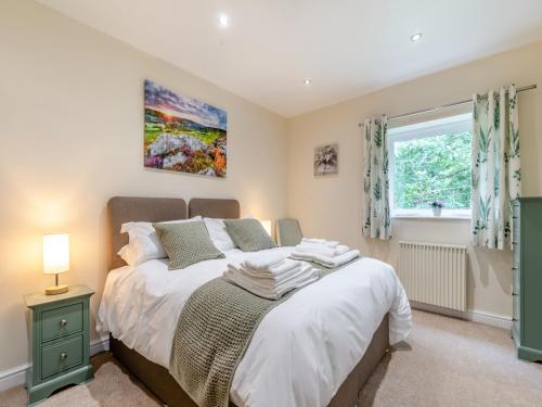 Schlafzimmer mit einem Bett und einem Fenster in der Unterkunft Woodlands Barn in Chinley