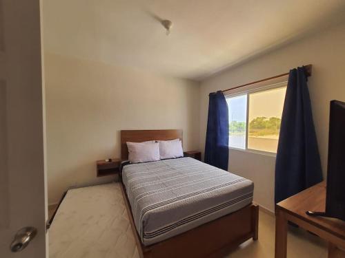 een slaapkamer met een bed met blauwe gordijnen en een raam bij Casa de 3 habitaciones TODAS con baño propio, 3 y medio baños en toal, alberca, cupo hasta 12 personas in Playa del Carmen