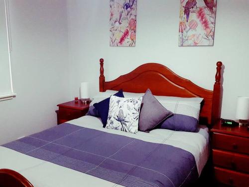 a bedroom with a bed with purple sheets and pillows at Wild Brumby- A cozy home away from home in Corryong